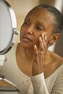 woman touching her face and looking in mirror