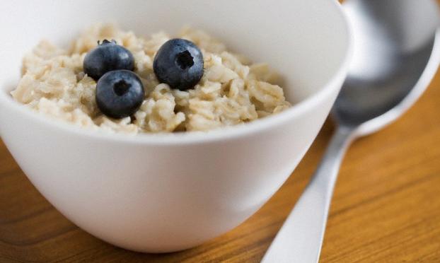 A bowl of oatmeal with three blueberries