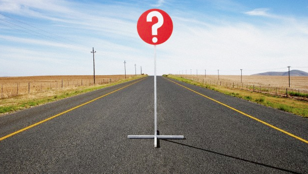 A question mark stop sign sitting on an open road
