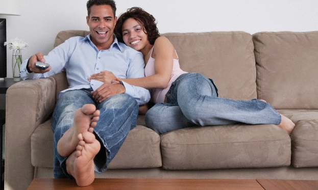 A couple on the sofa, the man holding a tv remote