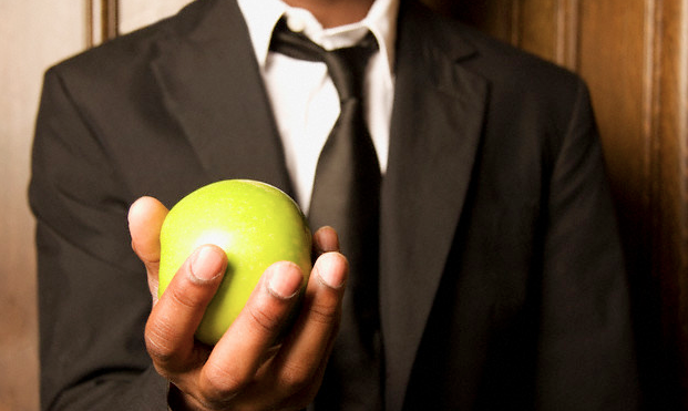 A man in a suit holding an apple