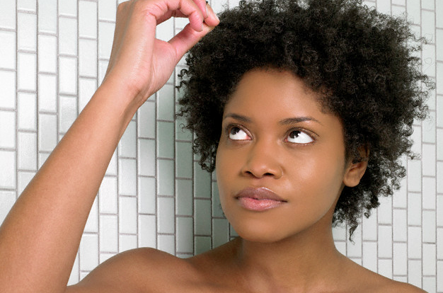 A woman pulling at a strand of her hair as she looks at it