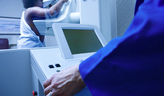 A black woman standing in front of a mammography device
