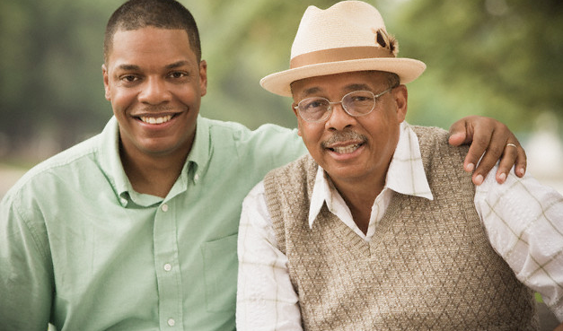 An adult son posing with his senior father
