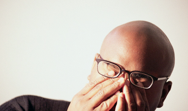 A man with glasses rubbing his eyes