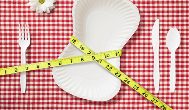 A tape measure wrapped around a white plate against a red checkered background