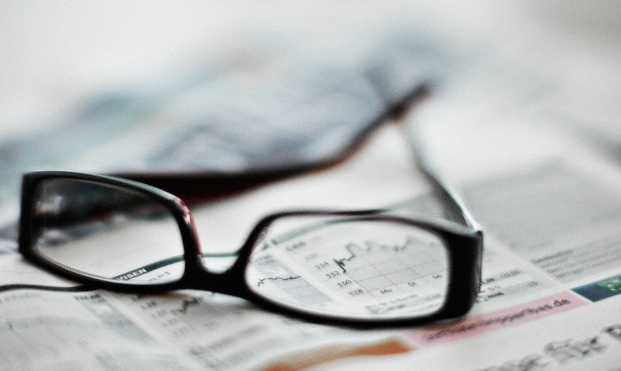 A pair of eye glasses sitting on a newspaper