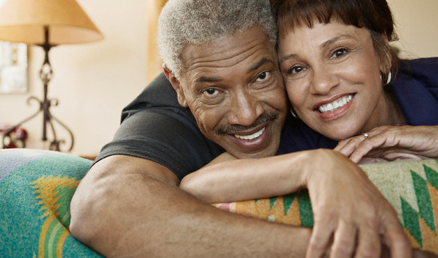 An older couple smiling and cuddling on the couch