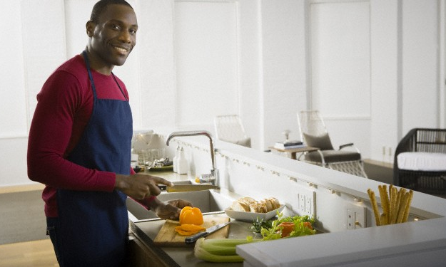 A man holding a yellow bell pepper in his kitchen