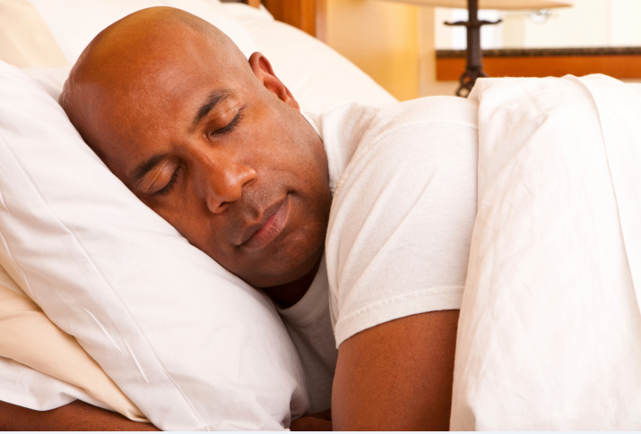 A man sleeping in his bed with his head on a pillow