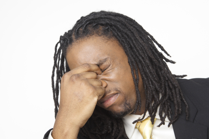 black businessman eyes closed pinching top of nose 