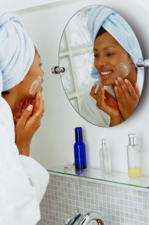 african american woman washing her face in the bathroom mirror