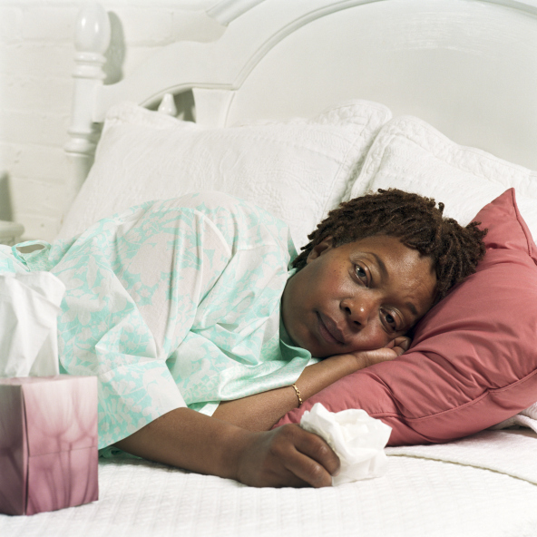 woman laying in bed with tissue