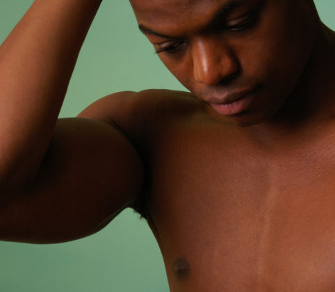 african american male on aqua background with his hands to his head.