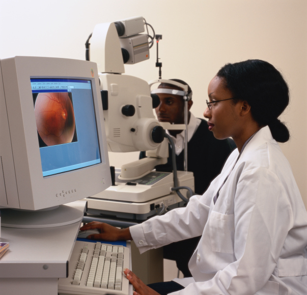 A female doctor examining a patient's eye on a computer monitor