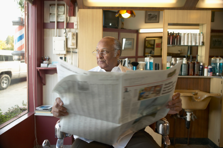 Senior man reading a newspaper in a barber shop