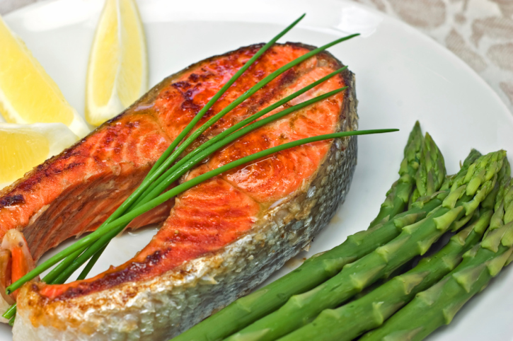 salmon steak dinner with asparagus and a lemon wedge