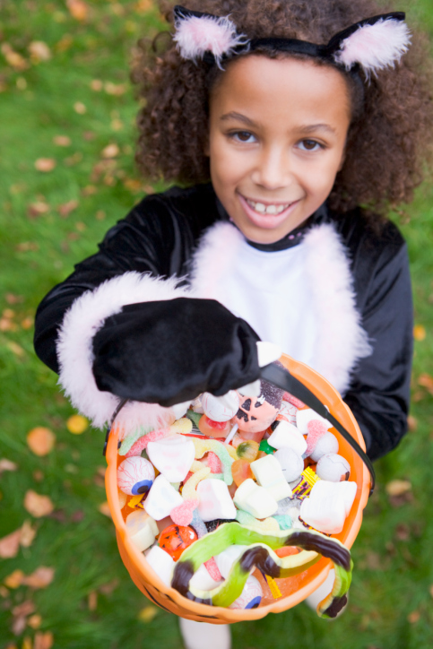 young african american girl holding halloween candy in a jack o latern