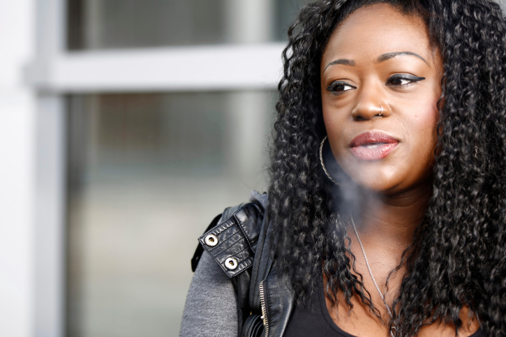 african american woman blowing out cigarette smoke