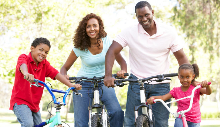 young family riding bikes in the park