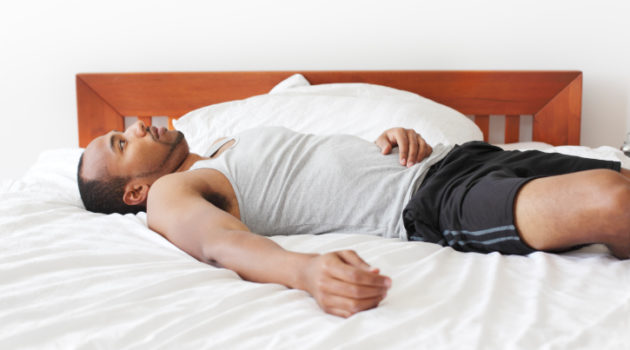 man laying in bed, awake and irriatated