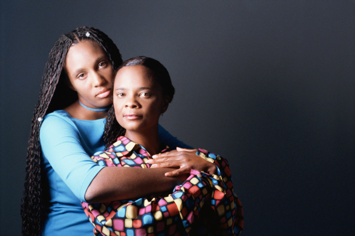 African American Black mother and daughter serious hugging