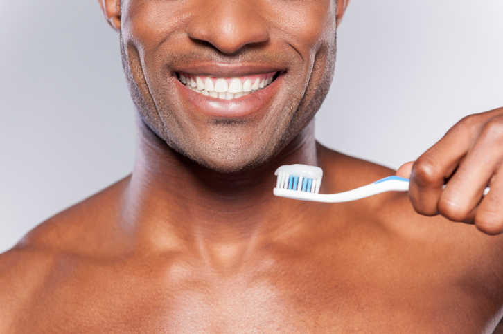 african american man smiling while holding a toothbrush
