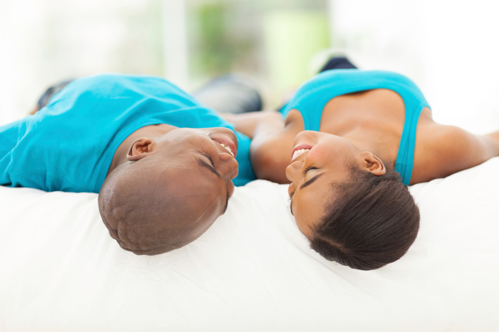 couple laying in bed looking at each other