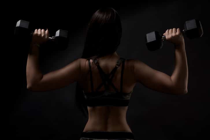strong tanned beautiful sports girl on a black background.