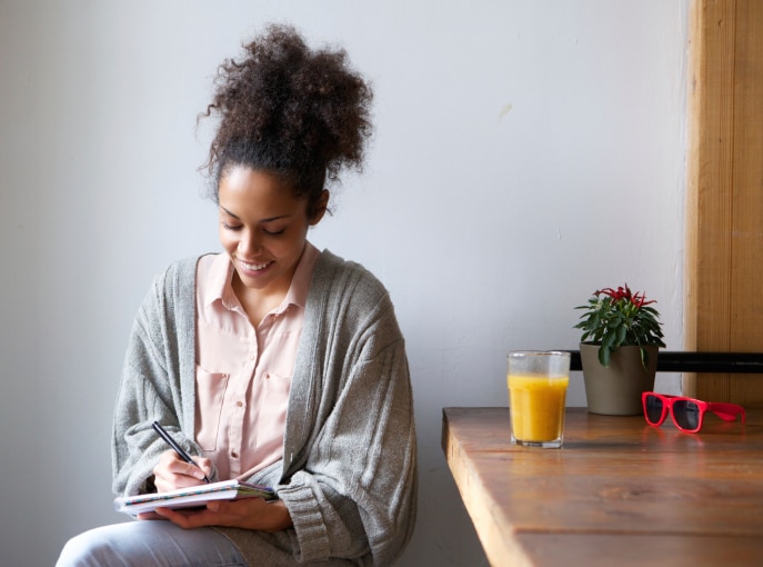African American Black Smiling woman writing on note pad at home