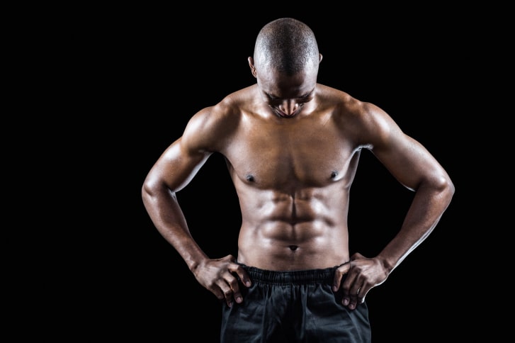 Muscular man with hand on hip looking down