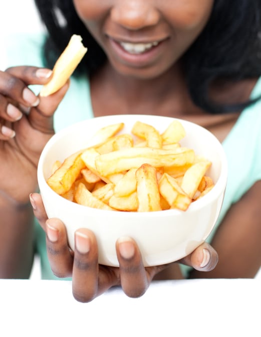African American teen girl eating bowl of fries