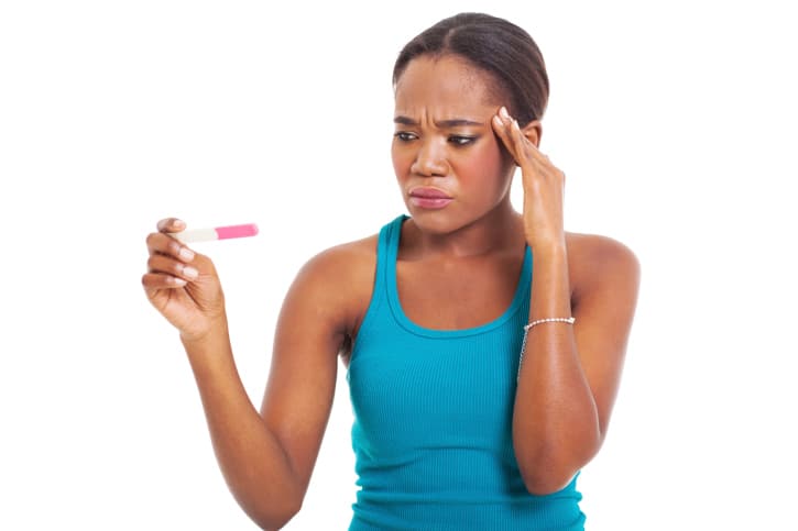 African American women looking confused upset at pregnancy test
