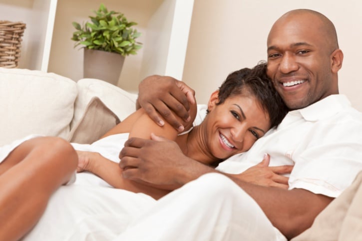 Happy African American couple hugging on couch