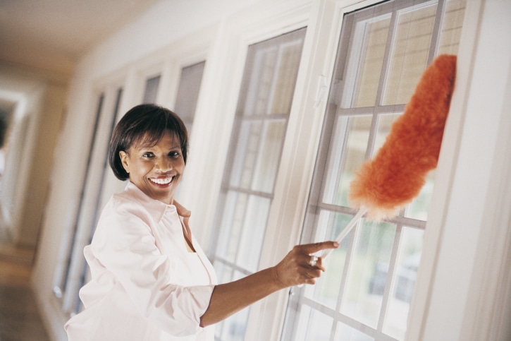 African American woman dusting home windows