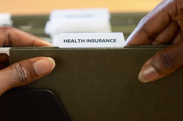 African American woman looking through health insurance folder