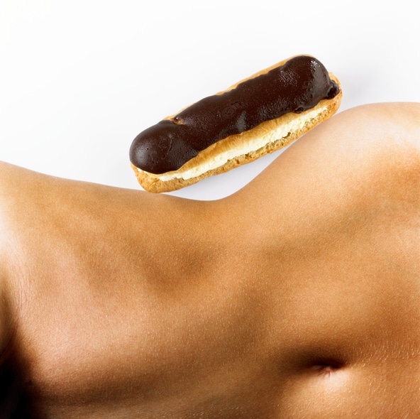 Woman with chocolate eclair 'balanced' on hip, mid section