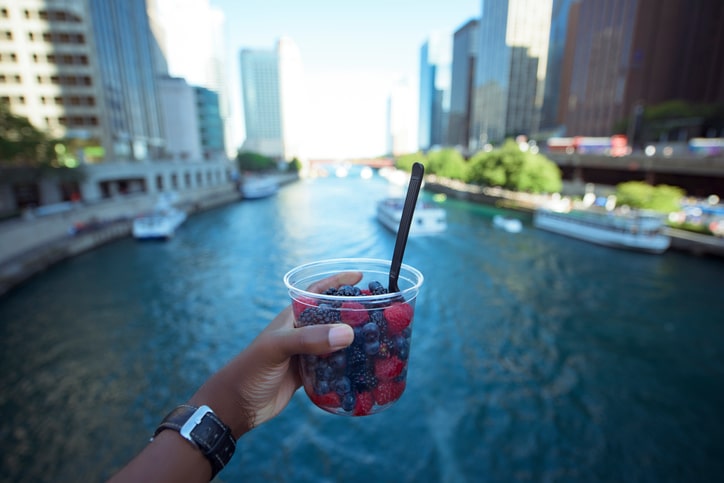 African American holding cup of blueberries and raspberries