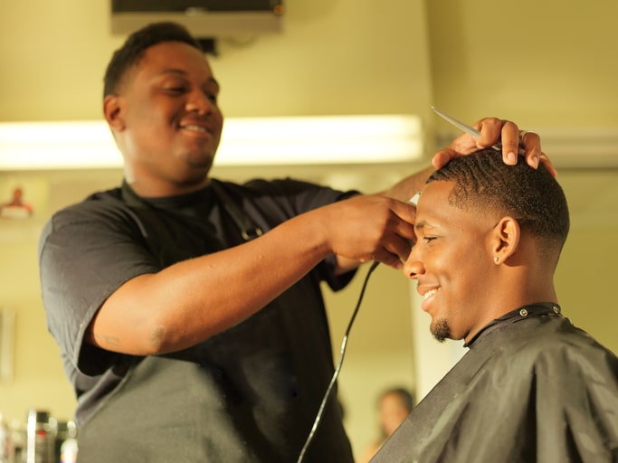 African American man getting hair cut at barbershop