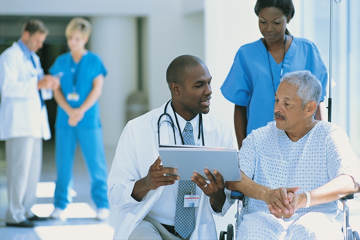 African American doctor talking to male patient in hospital