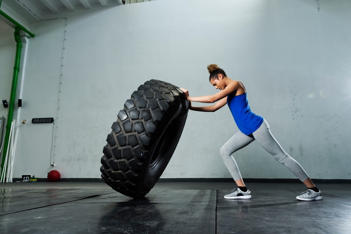 Young african american woman fit flipping tire