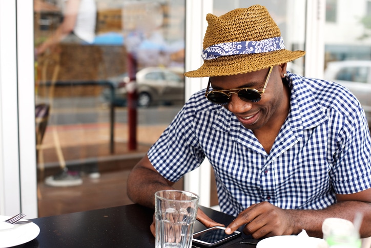 African American man on phone eating outside