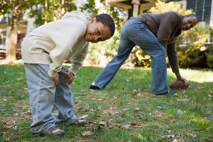 African American father and son playing football