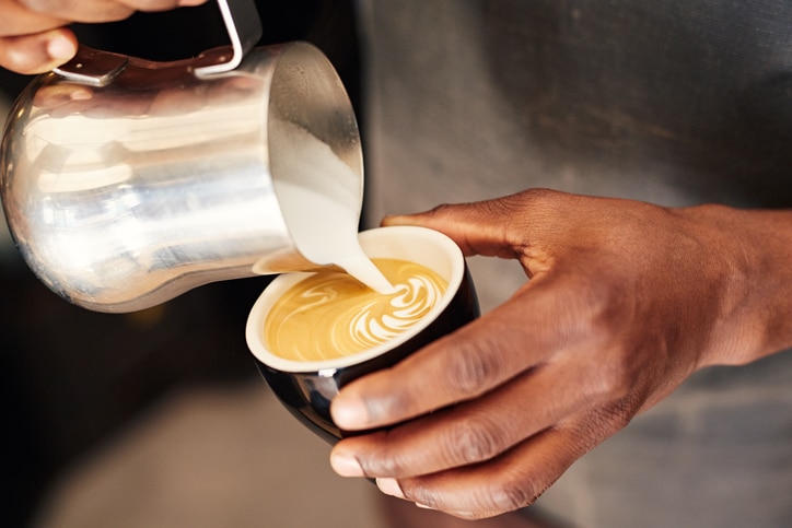 African American hands pouring milk into coffee