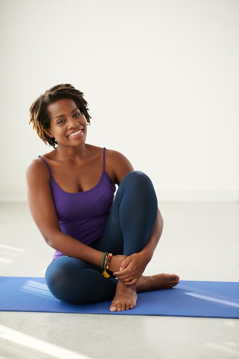 Happy African American woman exercising on yoga mat
