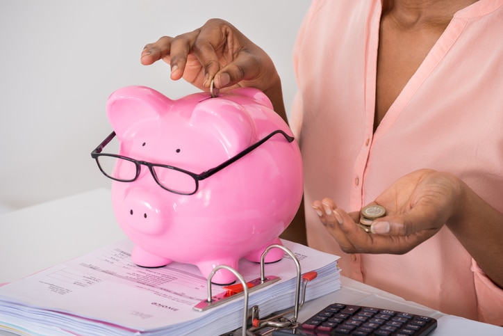 African American woman putting coins in piggy bank