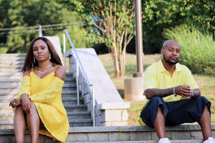African American couple sitting apart outside