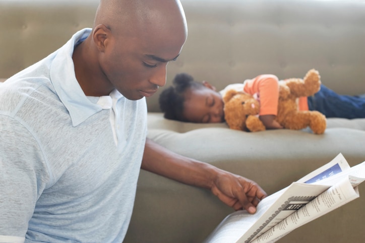 African American man father reading daughter sleeping