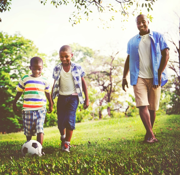African American father and sons playing ball outside