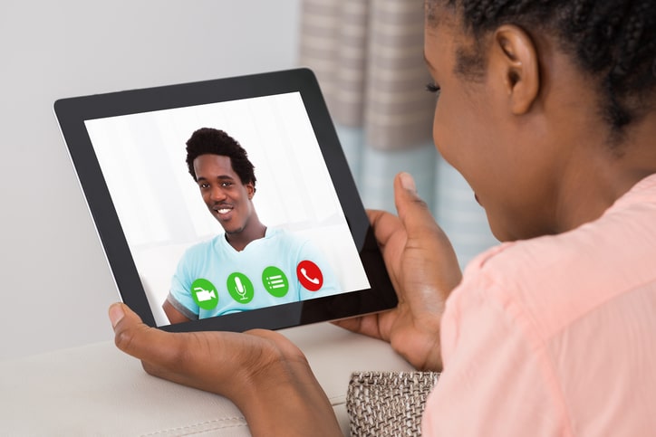 African American woman talking to man via tablet video